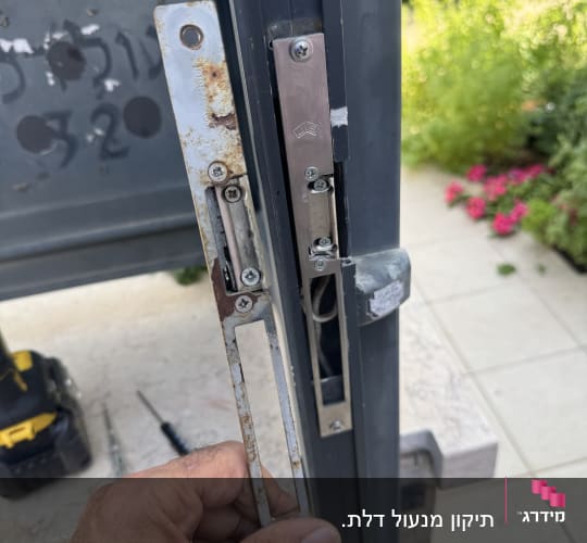 יד מחזיקה מנעול על דלת עם כלים ברקע